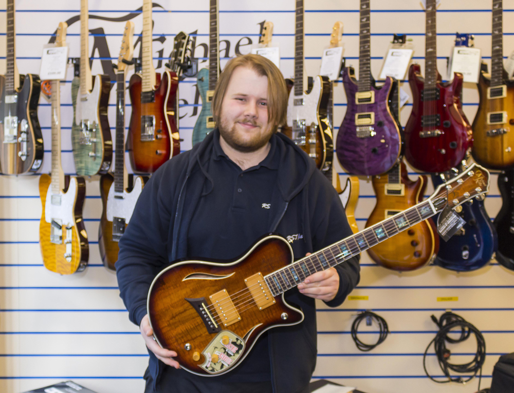 RST Music staff holding a Michael Kelly Hybrid guitar