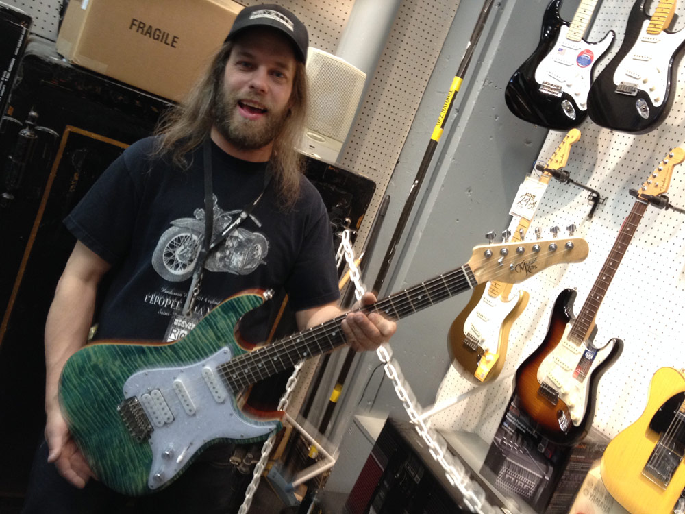 Steve's Music staff holding a Michael Kelly 1960s electric guitar Steve's Music staff holding a Michael Kelly 1960s electric guitar