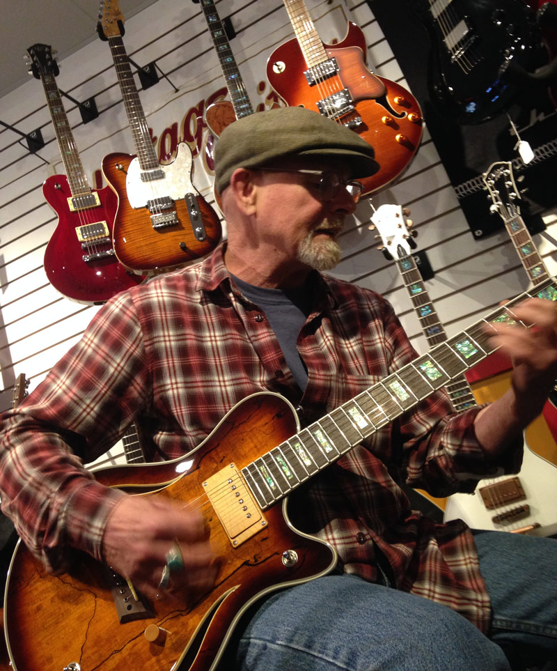 Warren's Music staff playing a Michael Kelly acoustic-electric Hybrid guitar