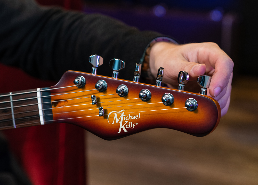 hand turning tuner on electric guitar headstock