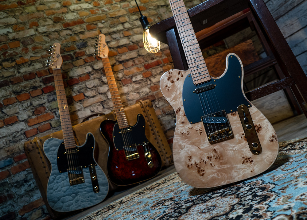 three electric guitars against brick wall
