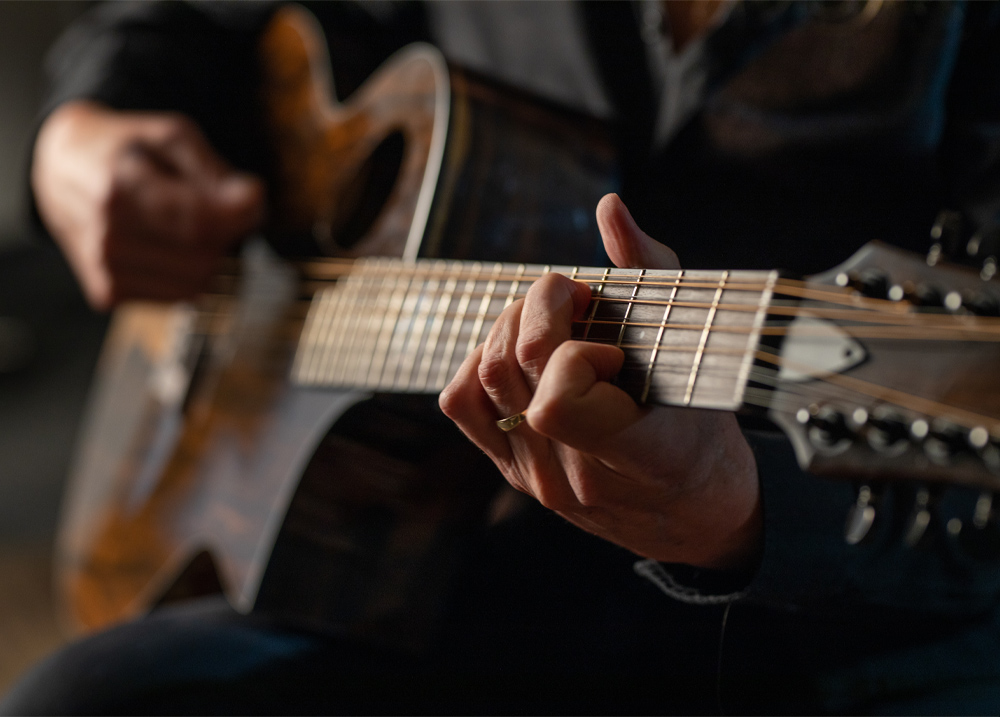 musician's hands playing acoustic guitar